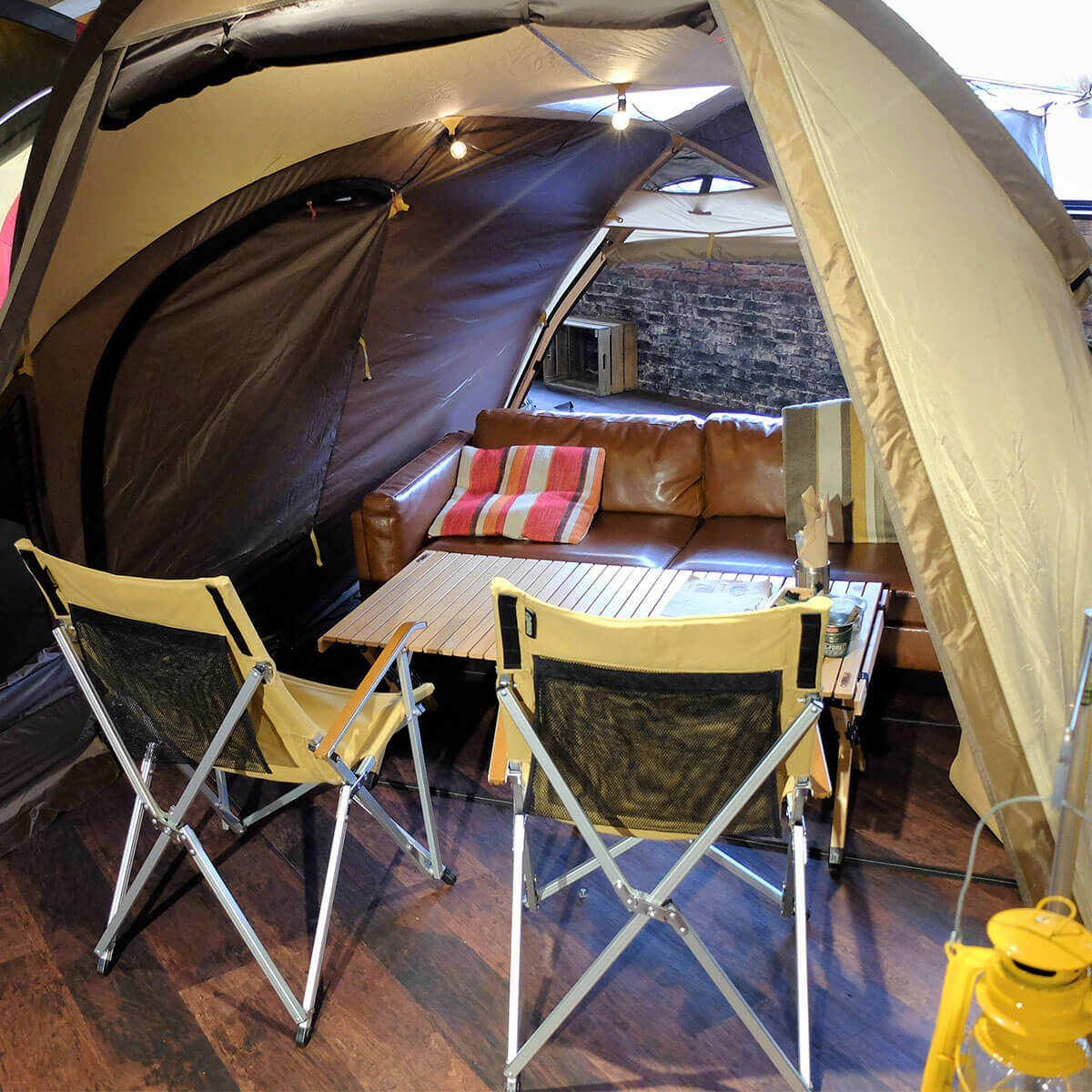 アウトドアチェアとテーブル、ソファが置いてあるテント